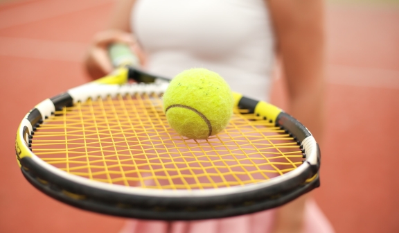 Closeup of a tennis ball placed on a racket